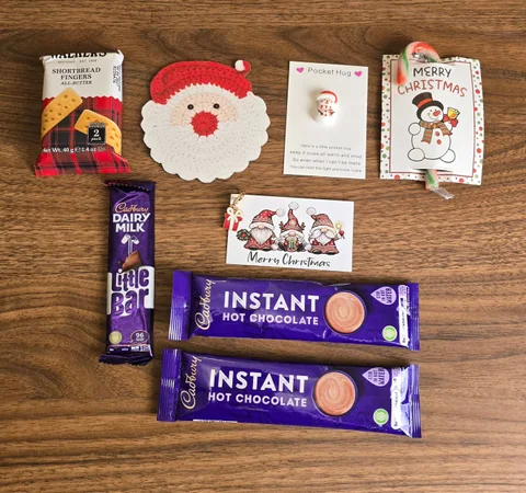 Christmas gift contents laid out, including treats, festive cards and a crocheted Santa